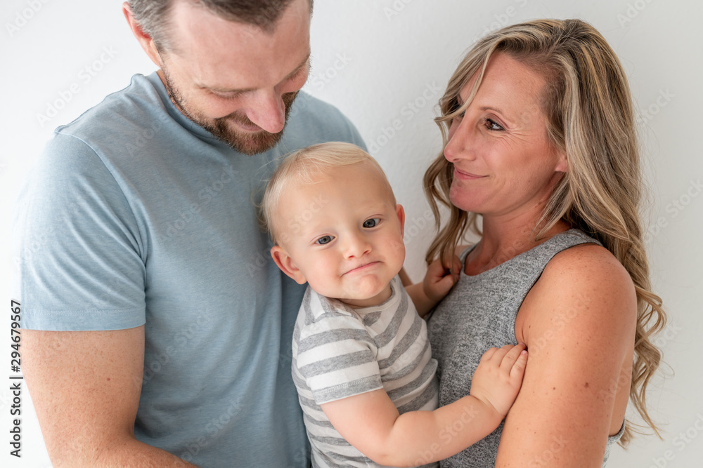 A Mother Smiling At Her Husband while The Baby Makes A Funny Face A Mother Smiling At Her Husband while The Baby Makes A Funny Face