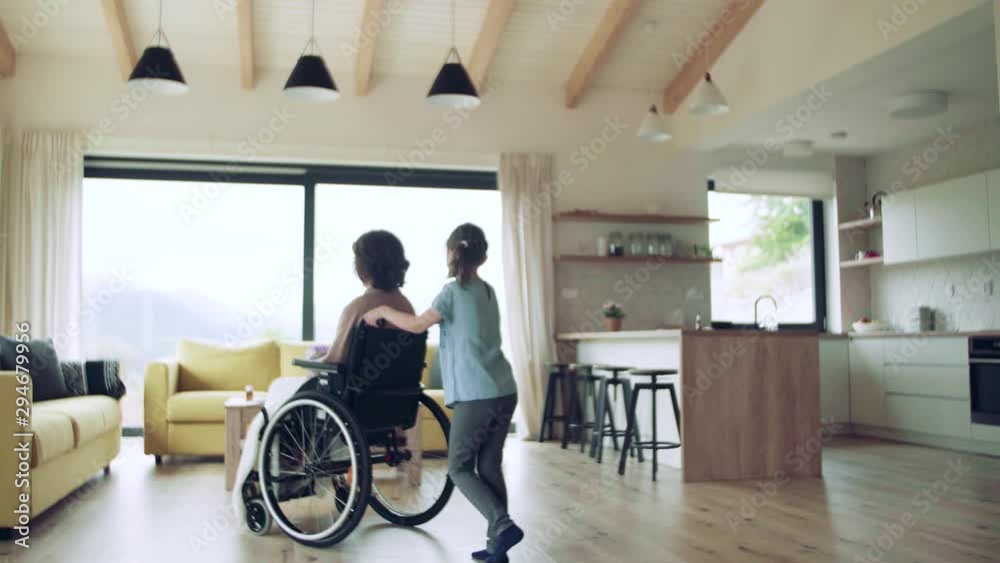 Small girl and her senior grandmother in wheelchair indoors at home. Small girl and her senior grandmother in wheelchair indoors at home.