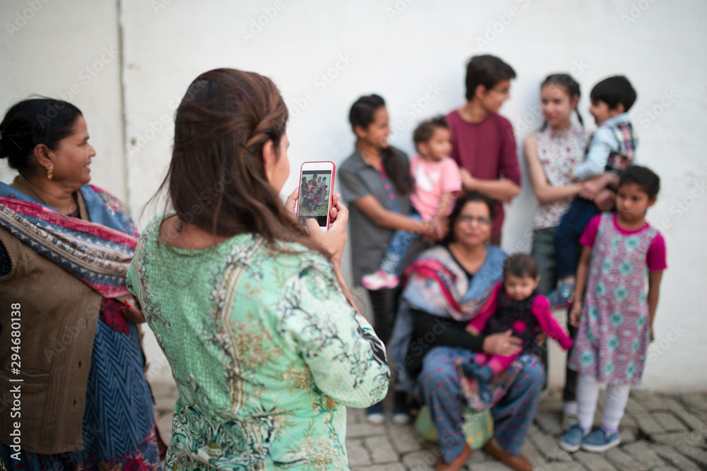 Woman taking picture of family group with her cell phone Woman taking picture of family group with her cell phone
