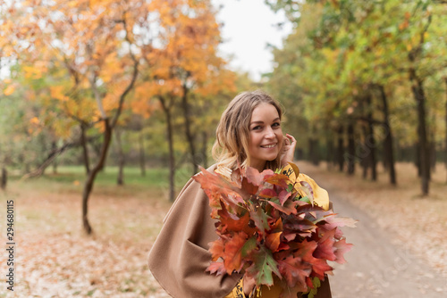 Attractive blonde with an armful of leaves in autumn park