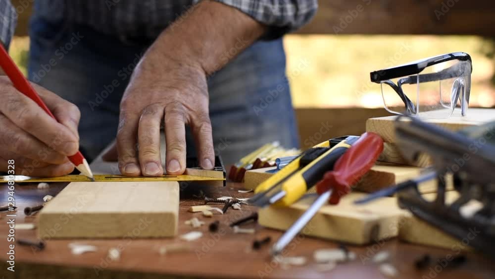 Adult carpenter craftsman takes the measure and with the carpenter's square trace the cutting line on a wooden table. Construction industry, housework do it yourself. Footage. Adult carpenter craftsman takes the measure and with the carpenter's square trace the cutting line on a wooden table. Construction industry, housework do it yourself. Footage.