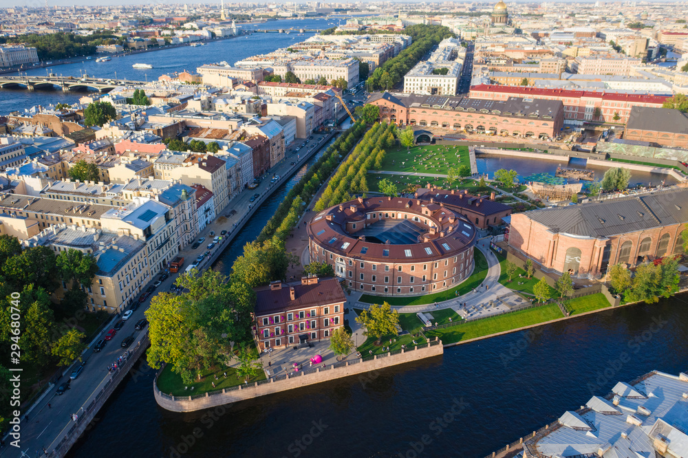 Aerial drone view of historical city part with old architecture and modern park between two artificial river channel, round building in the center, new Holland, Saint Petersburg, Russia