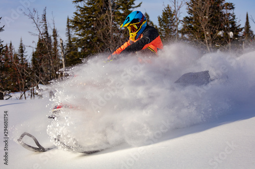 In deep snowdrift snowmobile rider make fast turn. Riding with fun in deep snow powder during backcountry tour. Extreme sport adventure, outdoor activity during winter holiday on ski mountain resort