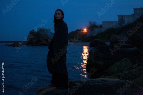 girl in a dark dress posing against the backdrop of the night sea photo