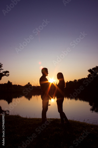 Silhouette of couple on the beach looking at sunrise. © Yekatseryna