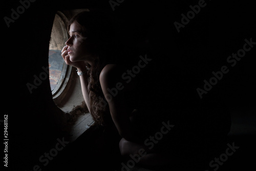 portrait of a girl at the window in the attic photo