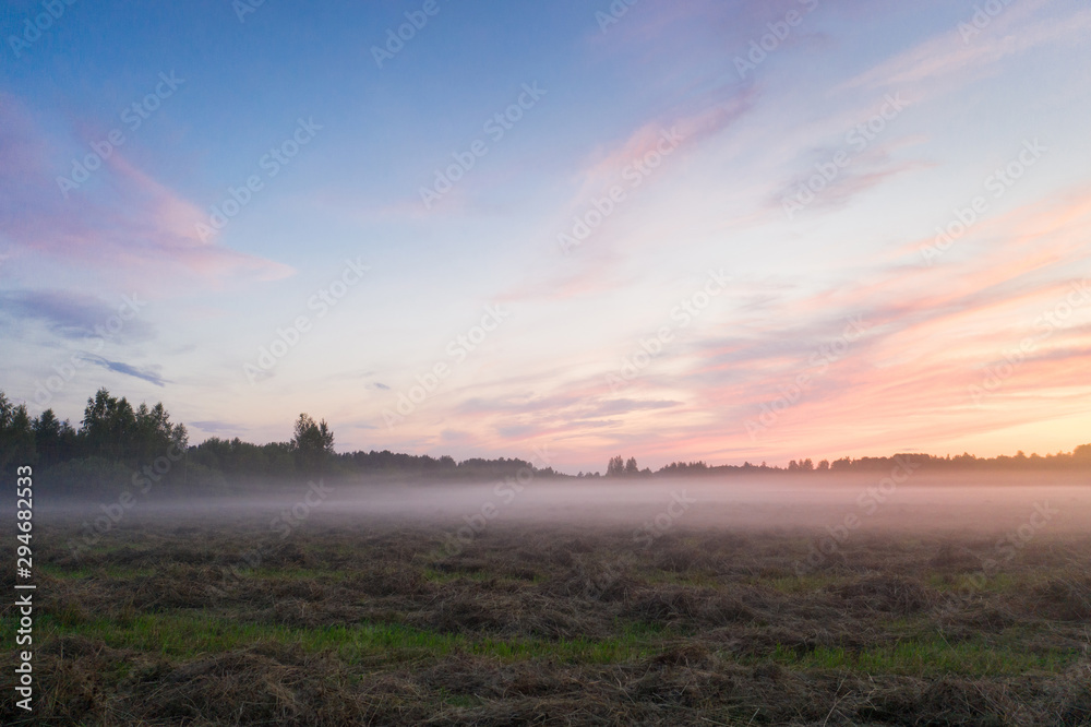 Magnificent sunset and mist spreading across the field, Leningrad region, Russia