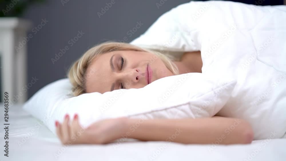 Adult woman sleeping under white douvet at home Adult woman sleeping under white douvet at home