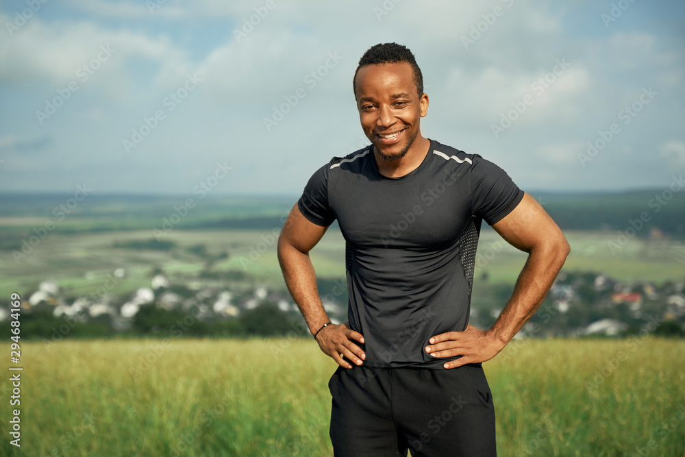 Smiling athlete holding hands on hips, posing.