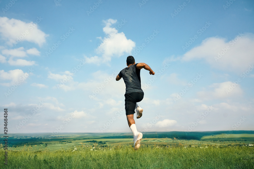 Back view of african athlete running on green grass. Back view of african athlete running on green grass.