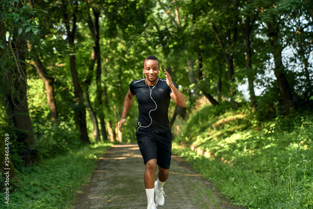 Athlete running in park walkway with headphones. Athlete running in park walkway with headphones.