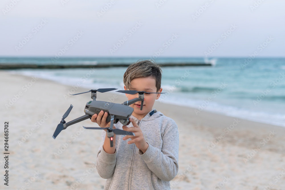 Handsome brunette boy with stylish haircut holds drone like airplane