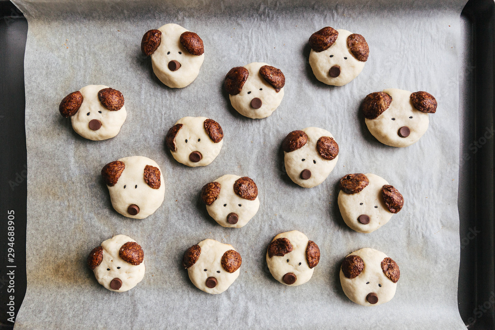 Dog shaped cookies with chocolate cereal ears on baking tray Dog shaped cookies with chocolate cereal ears on baking tray