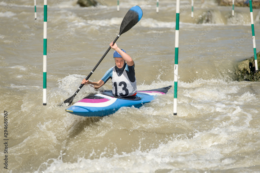 Naklejka premium White water kayak athlete racing through a downstream slalom gate