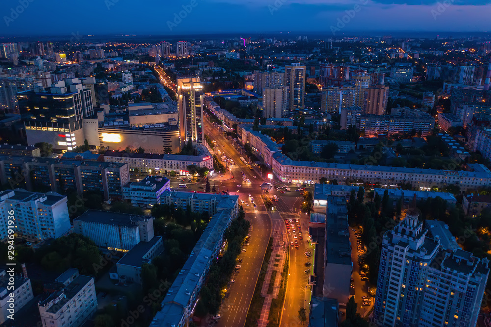 Aerial view of night city with illuminated roads, car traffic and different buildings, drone shot