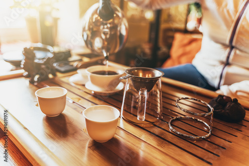 Chinese tea ceremony, girl makes boiling water from a teapot black tea puer in taiwan on wooden teatable in sunlight photo