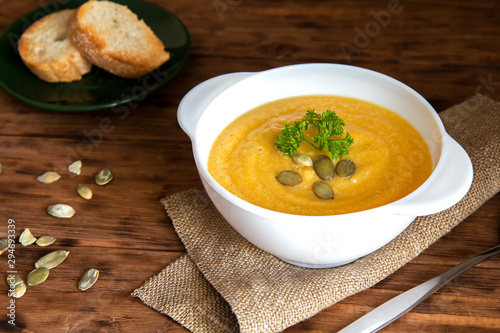 Pumpkin cream soup with croutons on a brown background