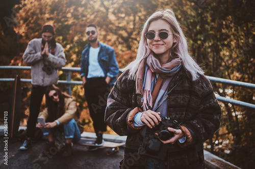 Young positive woman in sunglasses has a nice walk in bright autumn day.