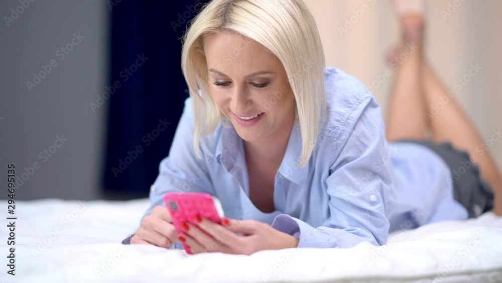 Adult woman relaxing at home and using smartphone Adult woman relaxing at home and using smartphone