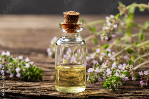 A bottle of essential oil with blooming creeping thyme