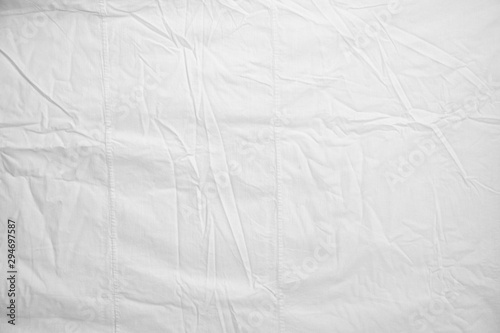 White Crumpled Bed Sheet Background Texture. white fabric top view. pleats on light fabric