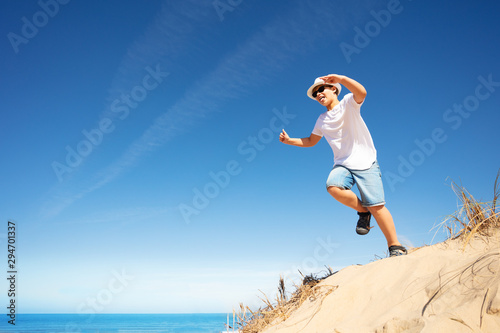 Cute boy in white jump from sand dune on a beach