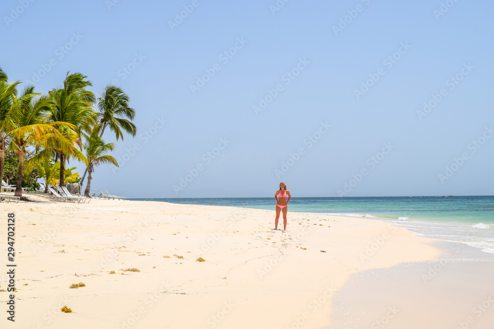 Woman standing on beach in the caribbean sea, white beach and blue sky, cayo levantado