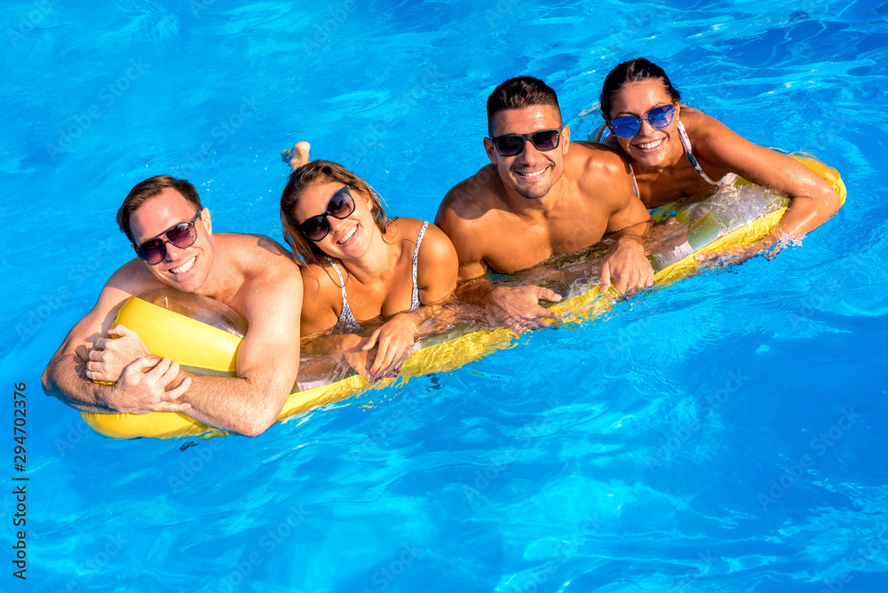 Group of young smiling cheerful people relaxing and having party in the swimming pool Group of young smiling cheerful people relaxing and having party in the swimming pool