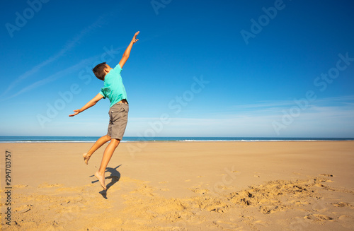 Happy careless boy jump high on the sea beach