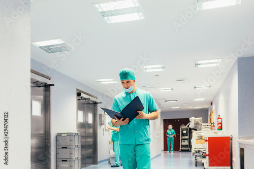 Surgeon Holding a Folder and Walking In Hospital Hallway photo