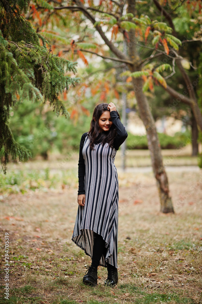 Portrait of young beautiful indian or south asian teenage girl in dress posed at autumn park in Europe. Portrait of young beautiful indian or south asian teenage girl in dress posed at autumn park in Europe.