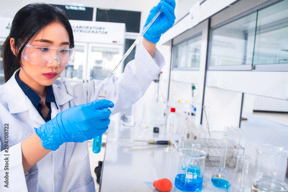 Interior of clean modern white medical or chemistry laboratory background. Laboratory scientist working at a lab with micropipette/pipette and test tubes. Laboratory concept with Asian woman chemist. Interior of clean modern white medical or chemistry laboratory background. Laboratory scientist working at a lab with micropipette/pipette and test tubes. Laboratory concept with Asian woman chemist.