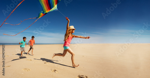 Girl and friends run fast on beach hold color kite