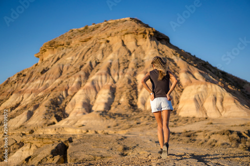 A young blonde with rocker look with high shoes on her back in the desert of the Bardenas Reales
