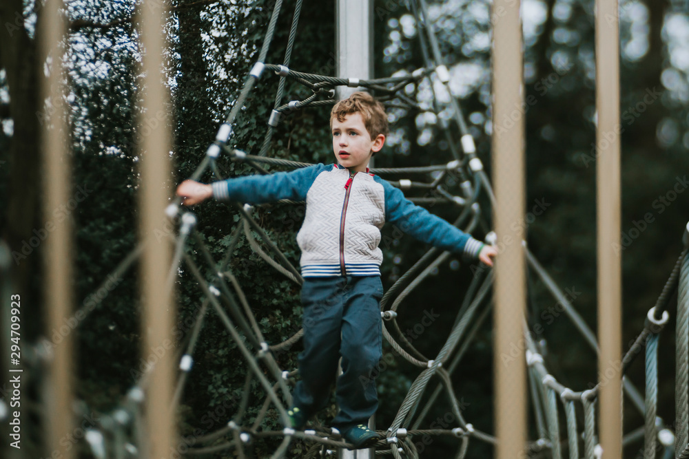 Boy balancing on climbing frame looking to the side Boy balancing on climbing frame looking to the side
