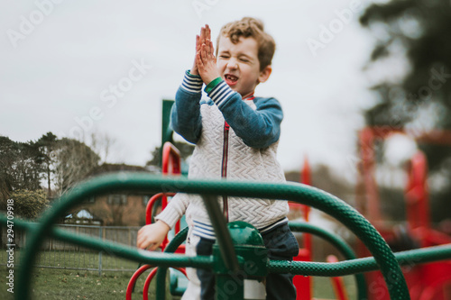 Side view of boy clapping on merry go round at playground photo