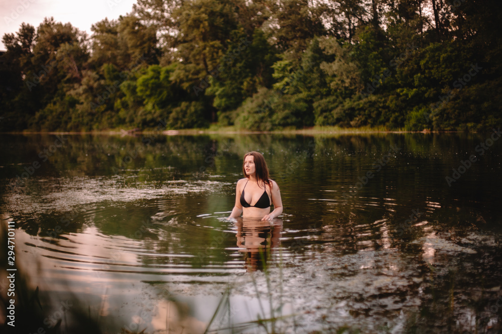 Young woman standing in lake against trees Young woman standing in lake against trees