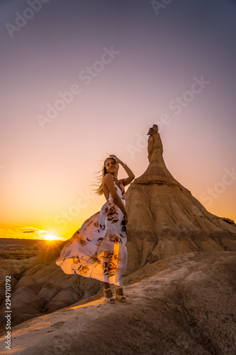 Lifestyle session of a blonde girl touching her hair in white dress on a sunset at the Castildestones de las Bardenas. Navarre