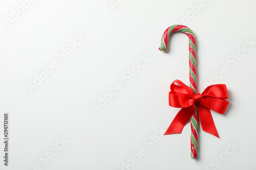 Sweet candy cane with bow on white background, space for text