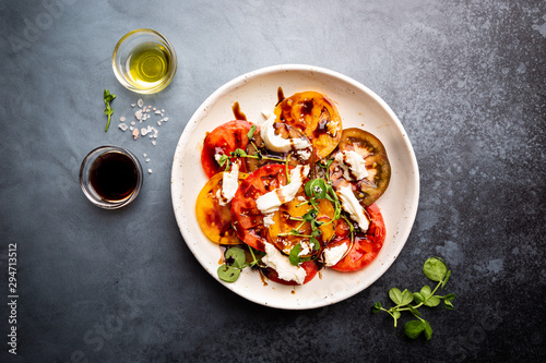 Tableau sur toile Fresh colorful tomatoes salad with mozzarella and balsamic vinegar on a plate, t