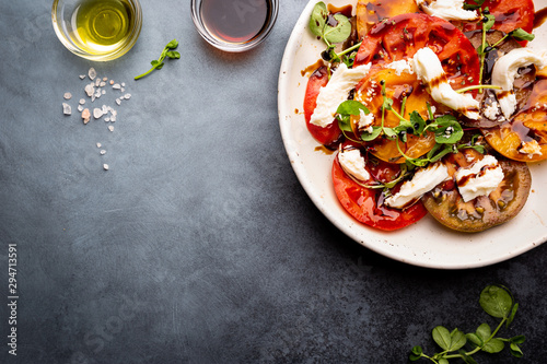 Fresh colorful tomatoes salad with mozzarella and balsamic vinegar on a plate, top view