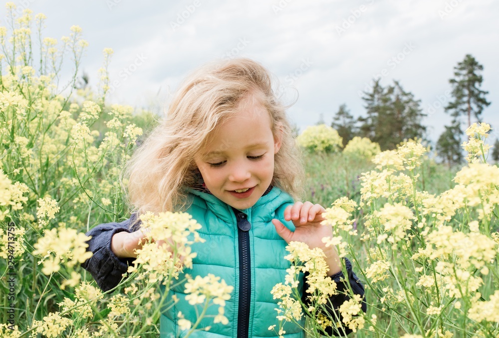 Young girl walking through a field of yellow flowers smiling Young girl walking through a field of yellow flowers smiling