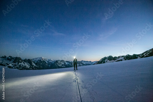 An alpinist uses a headlamp to navigate glaciated terrain pre dawn photo