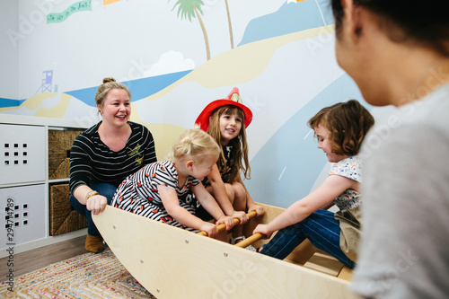 Teacher smiles as she rocks students in seesaw photo