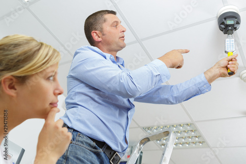 man testing the fire prevention system on ceiling photo