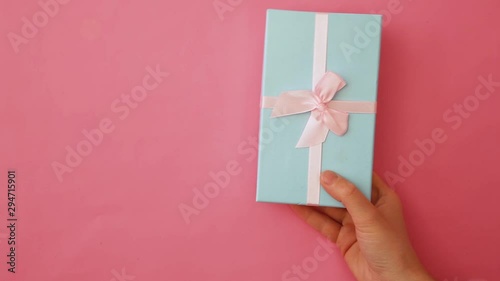 Simply design female woman hand holding blue gift box isolated on pink pastel colorful trendy background. Christmas New Year birthday valentine celebration present romantic concept. Copy space photo