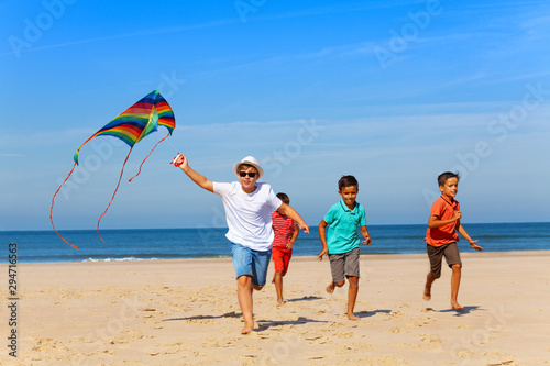 Group of children run on the beach with color kite