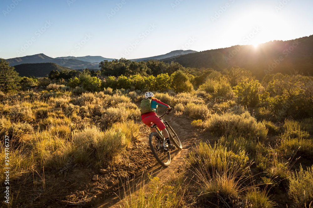 A woman riding a mountain bike outdoors just before sunset A woman riding a mountain bike outdoors just before sunset