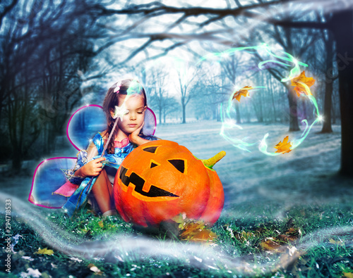 Girl in fee costume cast spells over big pumpkin © Sergey Novikov