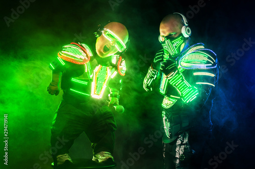 Mysterious man and midget in black wear  neon mask and gloves. Character pastors or wizards in robe from the future. Assassin with strong face expression. Fantasy book or computer game cover concept.